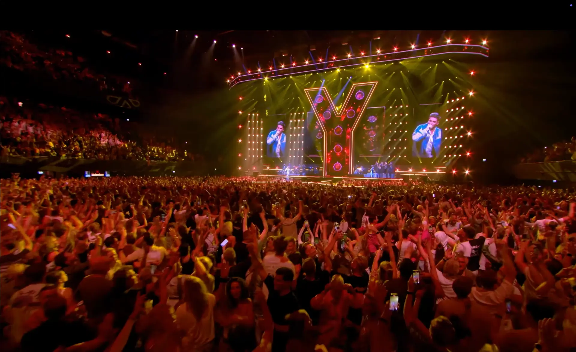 Arena audience at a live music show with a giant illuminated stage