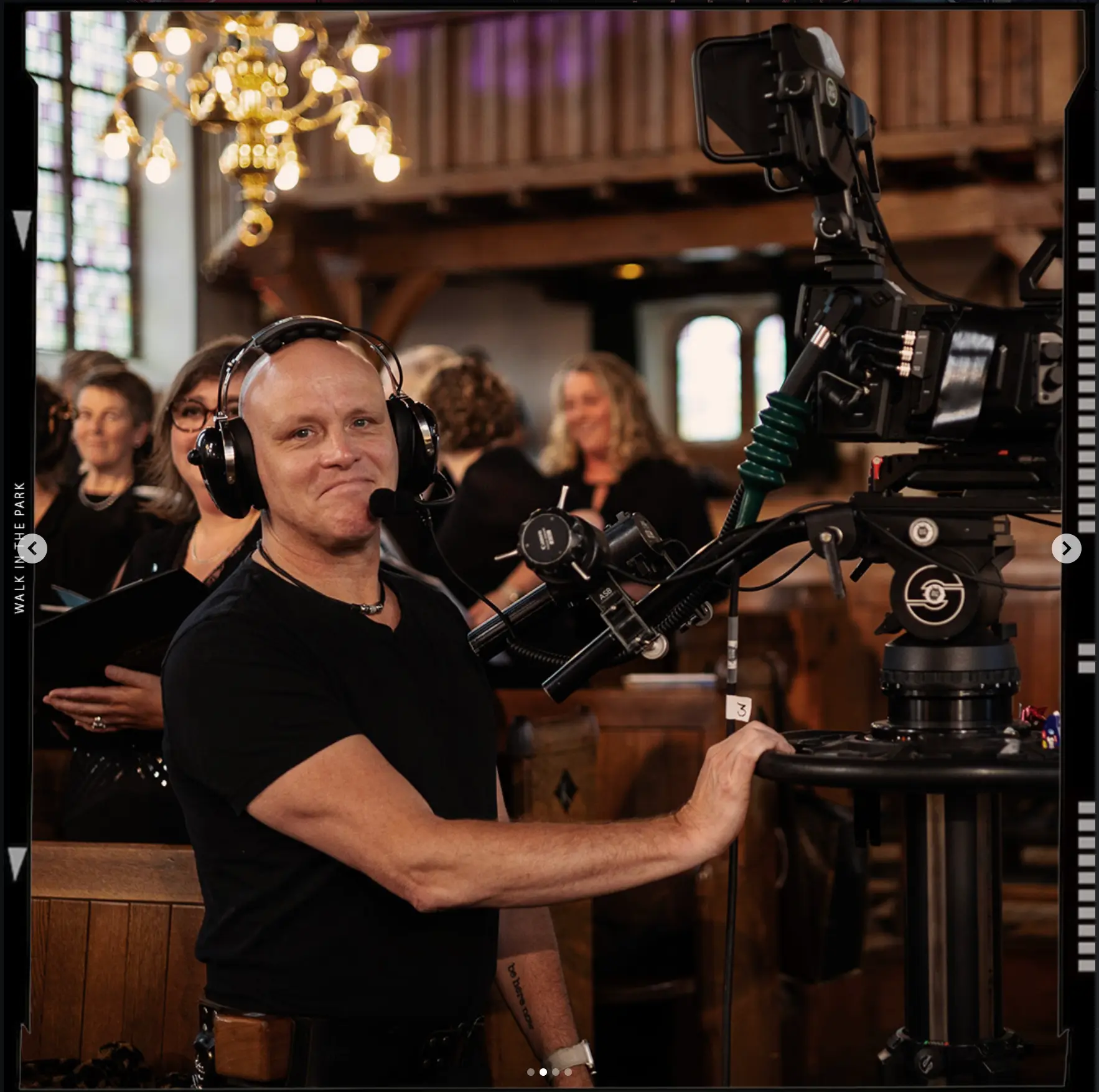 Smiling camera operator behind a pedestal camera in church