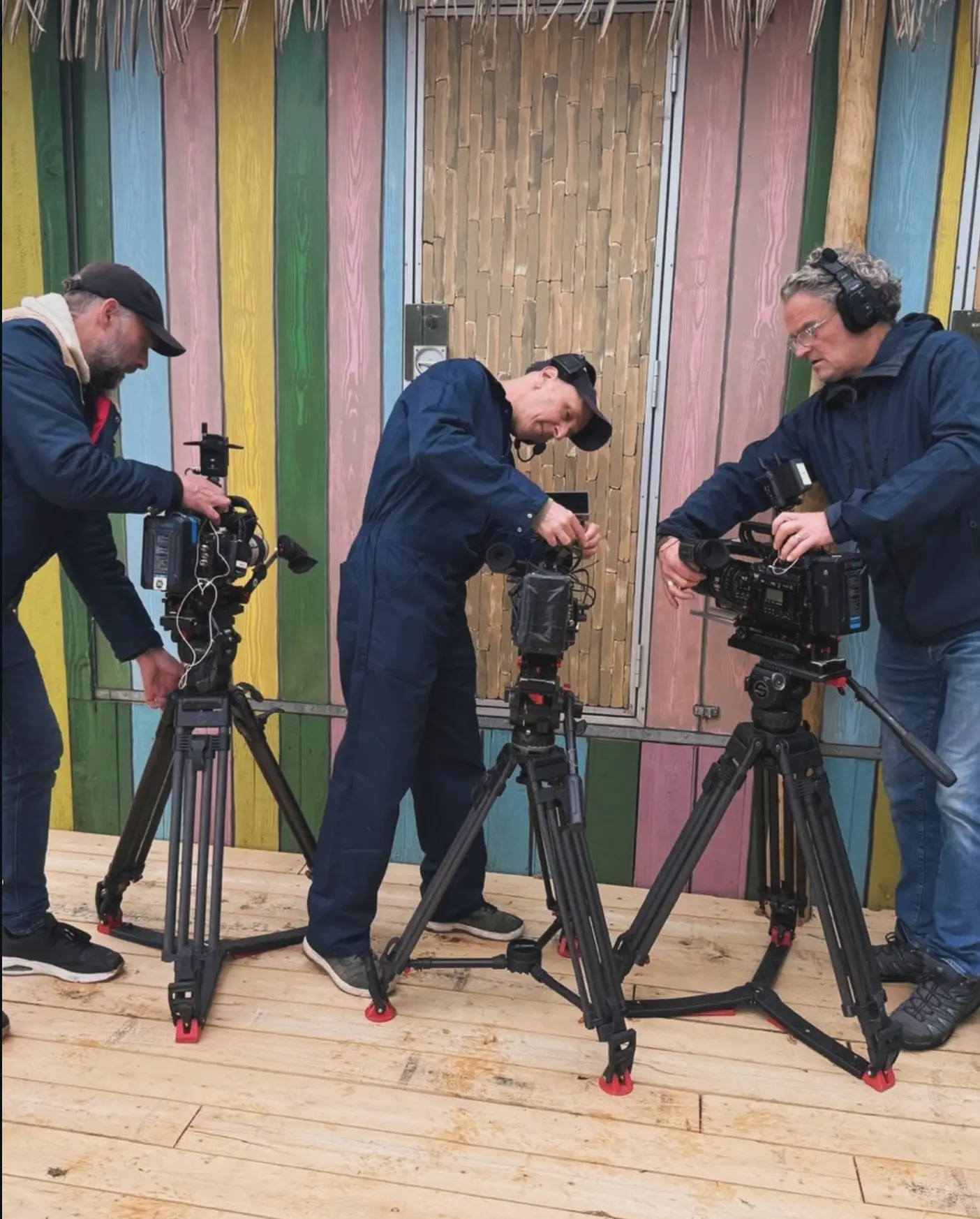 Three camera operators setting up tripods on location